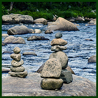Cairns on a rock in a creek. Encouraging the reader to get oriented to the site and what it is about.